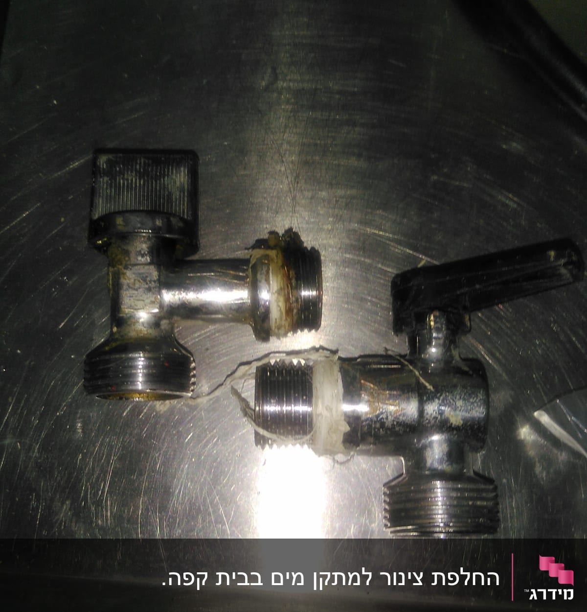 שני ברזים מתכתיים עם ידיות על משטח מתכת